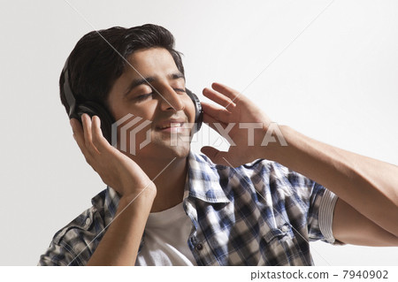 Relaxed young guy listening music over colored background Relaxed young guy listening music over colored background 7940902