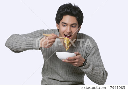 Hungry young man eating noodles 7941085