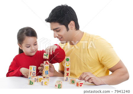 Father assisting girl in playing block game 7941240