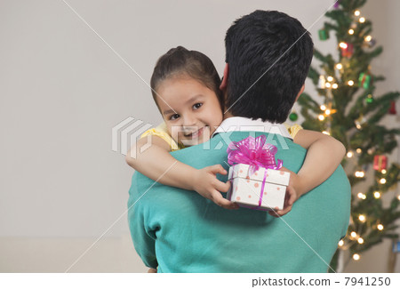 Happy young girl hugs her dad while holding Christmas gift 7941250