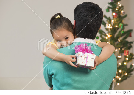 Girl hugs her dad while holding Christmas gift Girl hugs her dad while holding Christmas gift 7941255