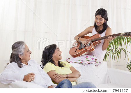 Girl playing guitar for her mother and grandmother Girl playing guitar for her mother and grandmother 7941257