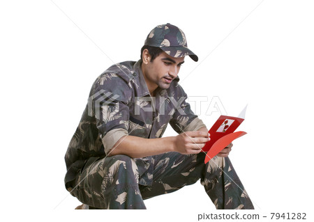 Smiling soldier reading greeting card 7941282
