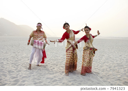 Bihu women dancing as Bihu man plays on a dhol 7941323