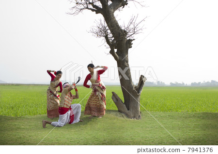 Bihu man playing on a pepa while Bihu women dance to his tune Bihu man playing on a pepa while Bihu women dance to his tune 7941376