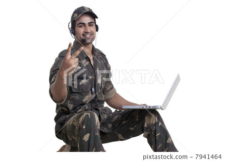 Portrait of soldier showing peace sign while using laptop 7941464