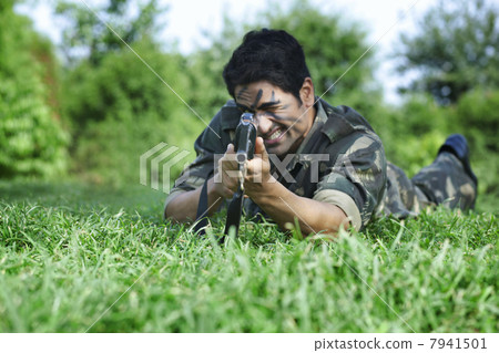 Army soldier aiming with rifle while lying on grass 7941501