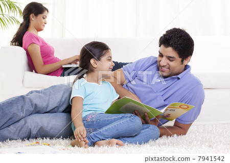 Father helping daughter in homework with woman using laptop in the background 7941542