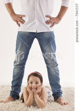 Portrait of cute girl lying between fathers legs on rug 7941577