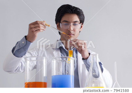 Lab technician adding solution to test tube 7941580