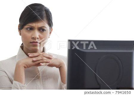 Businesswoman concentrating while looking at monitor screen Businesswoman concentrating while looking at monitor screen 7941650