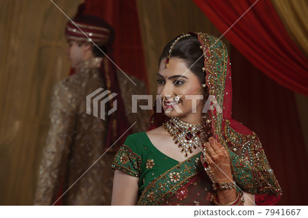Smiling bride with husband in the background 7941667