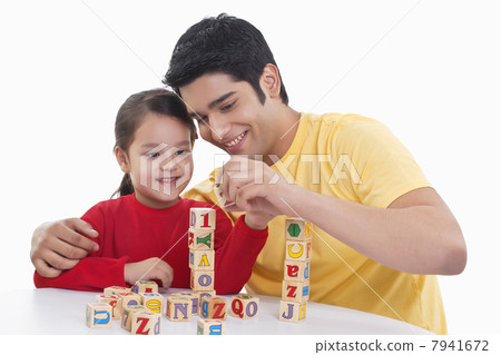 Smiling father assisting girl in playing block game 7941672