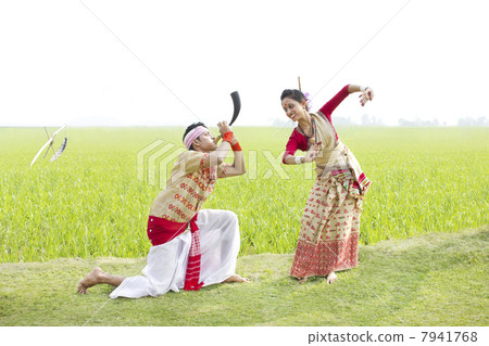 Bihu man blowing on a pepa while Bihu woman dances to his tune 7941768