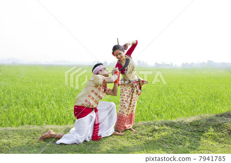 Bihu man blowing on a pepa while Bihu woman dances to his tune 7941785
