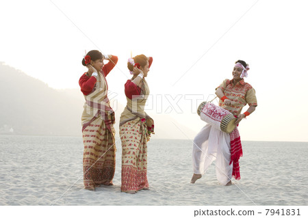 Bihu women dancing as Bihu man plays on a dhol 7941831