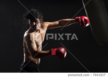 Handsome male boxer hitting heavy bag 7941837