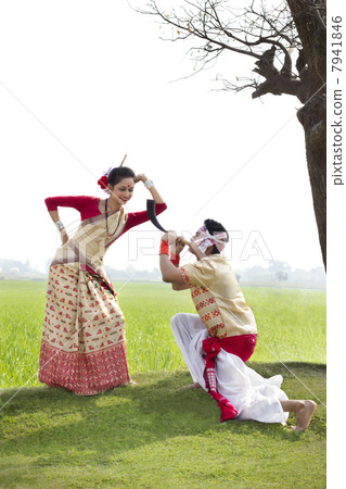 Bihu man blowing on a pepa while Bihu woman looks on 7941846