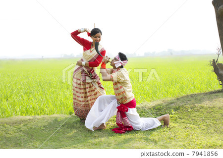 Bihu man blowing on a pepa while Bihu woman dances to his tune 7941856