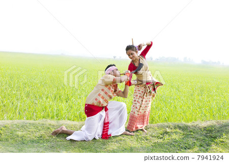 Bihu man blowing on a pepa while Bihu woman dances to his tune 7941924