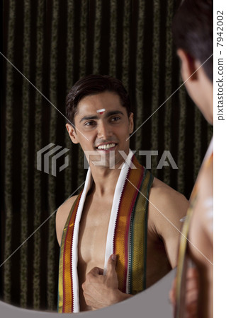 Young smiling man looking at self in mirror Young smiling man looking at self in mirror 7942002