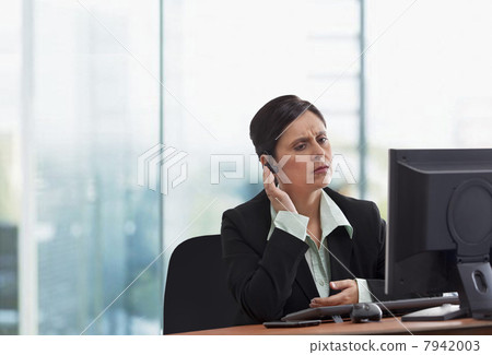Portrait of mature businesswoman on call while looking at computer Portrait of mature businesswoman on call while looking at computer 7942003