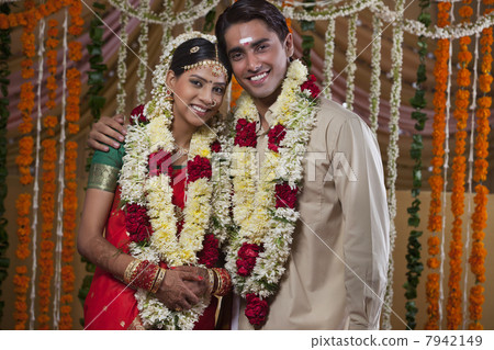 Portrait of young couple wearing garlands during traditional Indian wedding Portrait of young couple wearing garlands during traditional Indian wedding 7942149