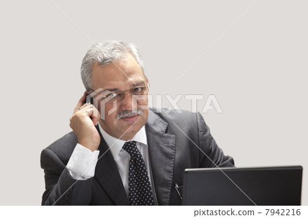 Mature businessman on call with laptop 7942216