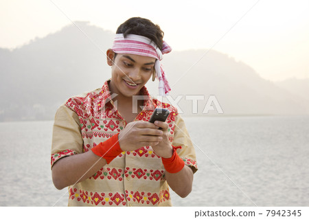 Bihu man reading an sms on a mobile phone Bihu man reading an sms on a mobile phone 7942345