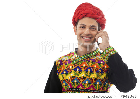 Male dandiya dancer talking on a mobile phone 7942365