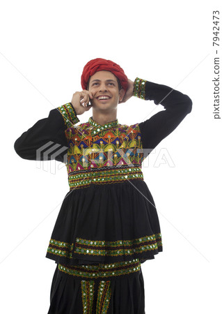 Male dandiya dancer talking on a mobile phone 7942473
