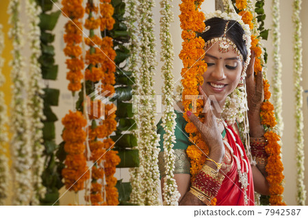 Young woman in traditional wear standing near garlands Young woman in traditional wear standing near garlands 7942587