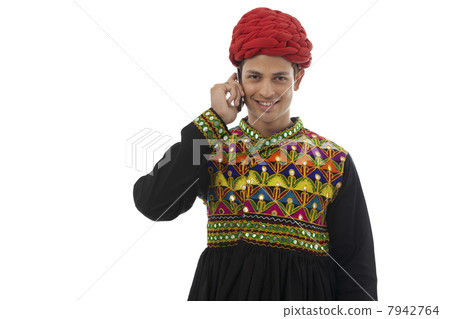 Male dandiya dancer talking on a mobile phone Male dandiya dancer talking on a mobile phone 7942764