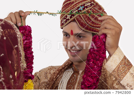 Gujarati groom putting a garland on a bride 7942800
