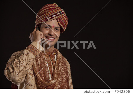 Portrait of a Gujarati groom talking on a mobile phone 7942806