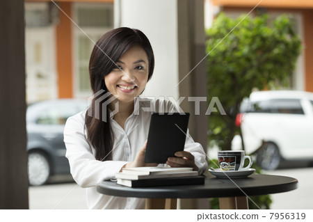 Chinese business woman using a tablet computer in a cafe. 7956319
