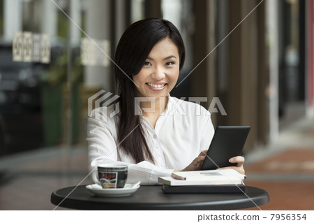 Chinese business woman using a tablet computer in a cafe. Chinese business woman using a tablet computer in a cafe. 7956354