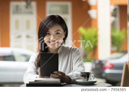 Chinese business woman using a tablet computer in a cafe. 7956365