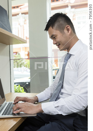 Chinese business man using a laptop computer. 7956393