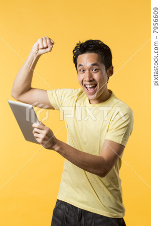 Happy Chinese man celebrating holding a Digital tablet 7956609