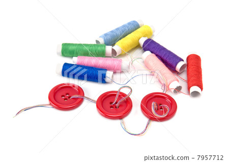 Red buttons and thread spools  on white background 7957712