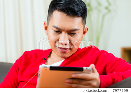 Young Asian man at home on the sofa 7977599