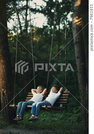 little boys riding on a swing 7981933