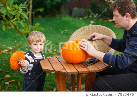 Young man and toddler boy making halloween pumpkin 7985476