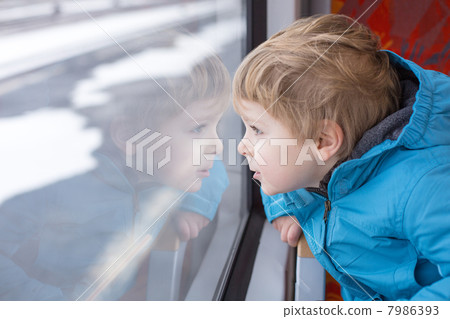 Cute little boy looking out train window 7986393