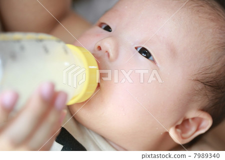 Baby drinking breast milk in a feeding bottle Baby drinking breast milk in a feeding bottle 7989340