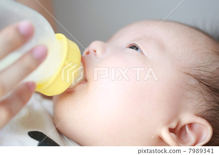 Baby drinking breast milk in a feeding bottle Baby drinking breast milk in a feeding bottle 7989341
