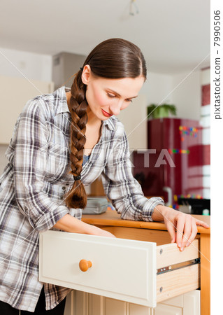 Young woman is assembling a cupboard 7990506