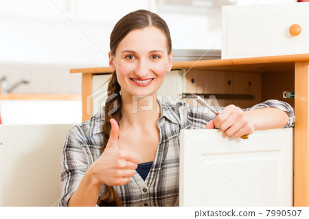 Young woman is assembling a cupboard Young woman is assembling a cupboard 7990507