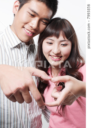 Portrait of a young couple embracing with hand in heart-shape 7993856